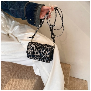 Detail of leopard print crossbody bag with silver buckles and chain strap on shoulder