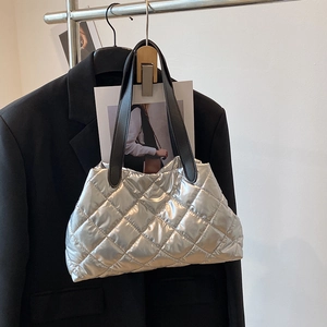 Silver quilted tote bag with black handles on a hanger against a white background
