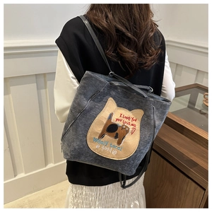 Close-up of a dark grey tote bag with a cute cat embroidery and casual lettering