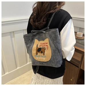 Detail of grey canvas backpack with cute cat patch worn by a model in casual setting