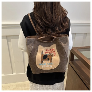 Detail of cute cat embroidery and text on dark brown canvas backpack for autumn commute
