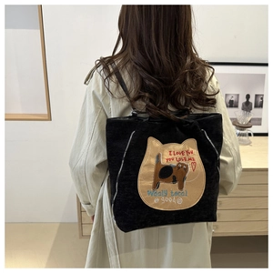 Detail of cute cat embroidery and textured corduroy fabric on a black tote backpack