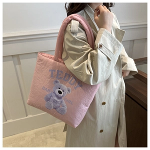 Detail of pink quilted tote bag with cute teddy bear prints and soft padded texture