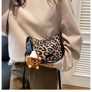 Detail of leopard print crossbody bag with fashion label and plush ball keychain