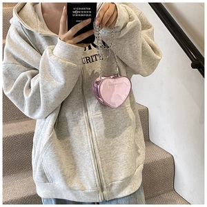 Detail of pink heart-shaped mini chain bag with glossy finish and silver metal strap