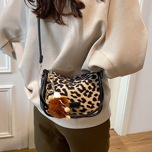 Stylish leopard print crossbody saddle bag with black leather trim and plush charm