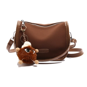 Brown half-moon crossbody bag with suede finish and cute plush monster charm