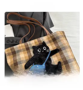 Détail d'un sac cabas en toile à carreaux avec broderie chat et finitions cuir