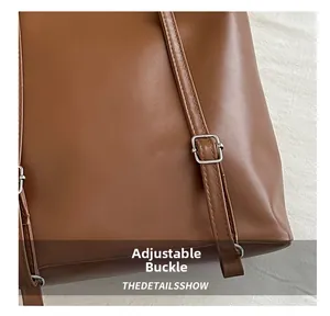 Détail de la bandoulière réglable et de la boucle en métal argenté du sac marron