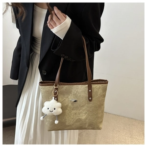 Dettaglio della borsa tote in tela verde oliva con finiture in ecopelle marrone e ciondolo
