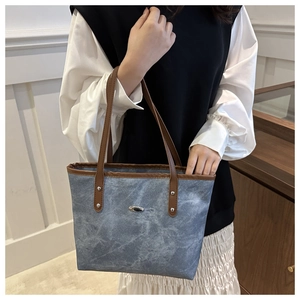 Dettaglio della borsa tote blu marmorizzata con manici in pelle marrone e finiture in metallo