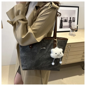 Dettaglio della grande borsa tote antracite con finiture in pelle marrone e charm a nuvola