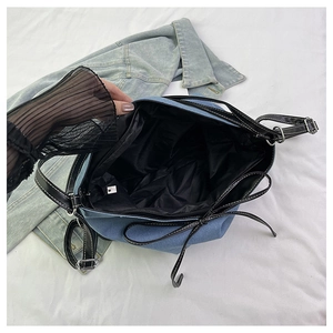 Detail showing internal black lining and metallic zipper of the blue denim tote bag