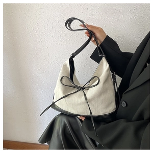 Detail of canvas tote bag featuring black leather trim and delicate bow knot decoration