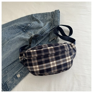 Detail view of navy blue plaid waist bag on denim jacket featuring adjustable strap
