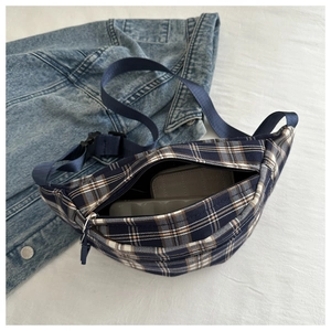 Detail view of plaid chest bag with dual zippers showing interior storage capacity