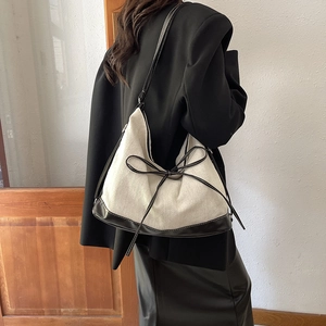 Minimalist monochrome tote bag with leather bow shown on shoulder in a lifestyle setting