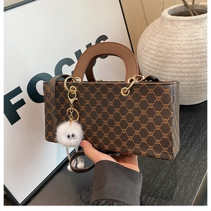Detailed view of kids vintage brown monogram box bag with a white plush doll charm