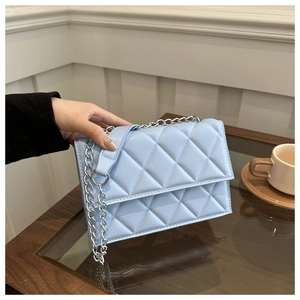 Detail of light blue quilted leather bag with silver chain strap and rhombus stitching