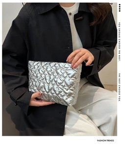 Détail de la trousse de maquillage argentée matelassée en cœur tenue par un modèle