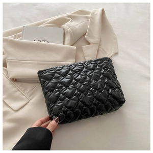 Détail d'une pochette noire avec matelassage en forme de cœur sur fond minimaliste