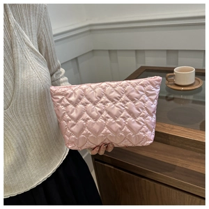 Détail d'une pochette en satin rose avec matelassage en cœur et texture soyeuse