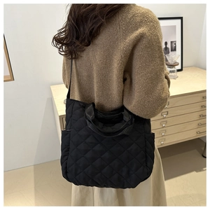 Detail of black quilted tote bag showing rhombus stitching and versatile carrying straps