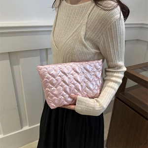 Pochette rose à surpiqûres cœurs en satin tenue par un mannequin au look décontracté