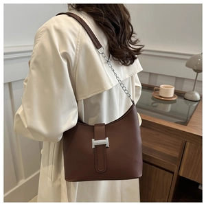 Detail of a brown leather shoulder bag featuring a silver H-shaped buckle and chain strap