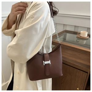 Close-up of dark brown leather underarm bag featuring a silver metal H-buckle and chain strap