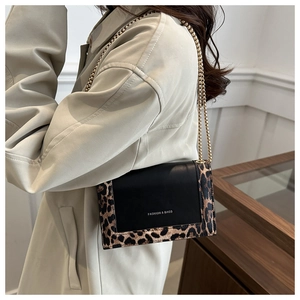 Detail of crossbody bag with leopard print trim and elegant gold chain strap