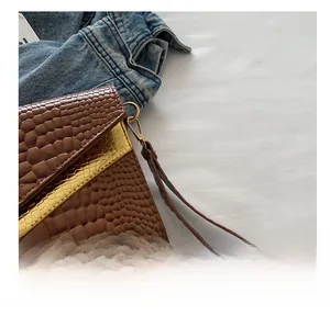 Close-up of brown crocodile pattern clutch bag with gold metal trim and leather strap