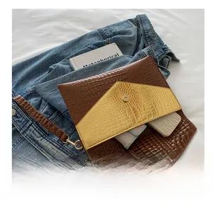 Detail view of crocodile pattern clutch bag interior showing spacious capacity and wrist strap