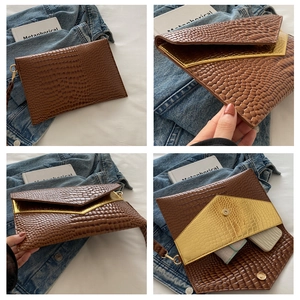 Detail view of brown crocodile texture envelope clutch with gold inner lining and magnetic snap