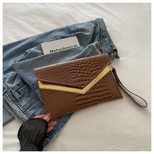 Detailed macro of brown crocodile texture and gold V-shaped metal on the envelope clutch