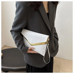 Detail of white crocodile pattern clutch bag with gold V-metal trim and wrist strap