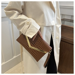 Close-up of brown crocodile texture envelope clutch bag with gold V-shaped metal trim