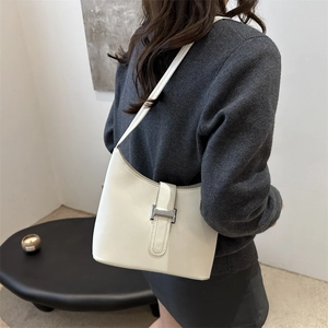Minimalist cream white hobo underarm bag with silver buckle shown on shoulder