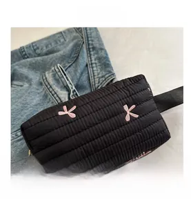 Detailed top view of black quilted clutch with pink bow embroidery and golden zipper