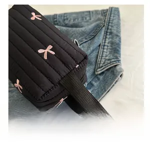 Close-up of black quilted nylon bag with pink bow embroidery and comfortable strap handle