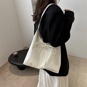 Minimalist white faux leather tote bag with bow detail shown on a female model