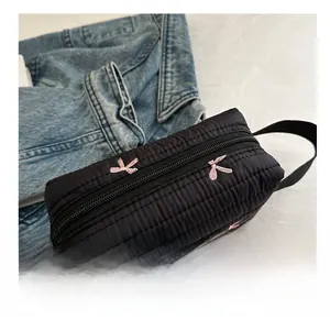 Detail view of black quilted pencil case with pink bow embroidery and zipper closure
