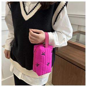 Close-up of fuchsia quilted handbag with elegant black bow embroidery details