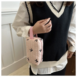 Detail of pink quilted pencil case featuring black bow embroidery and fabric handle