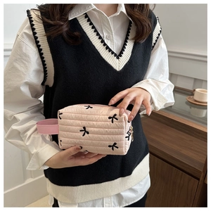Detail of pink quilted pencil case with bow patterns and gold zipper closure