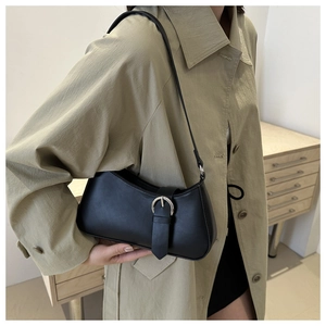 Detail of black leather underarm bag featuring a vintage silver buckle and slim shoulder strap