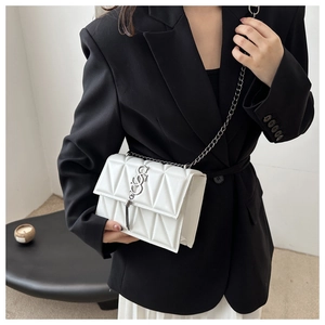 Close-up of white quilted leather crossbody bag with silver chain and tassel detail