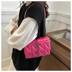 Detail of rose red quilted crossbody bag with silver SS metal logo and chain strap