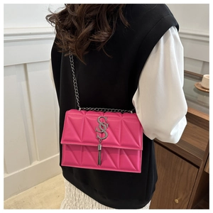 Detail of rose pink quilted crossbody bag with silver S-buckle and tassel on model