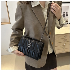 Close-up of black quilted leather crossbody bag with silver S logo and chain strap